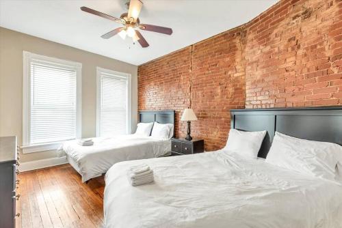 een slaapkamer met 2 bedden en een bakstenen muur bij St Louis Townhome Perfect for Groups in Tower Grove