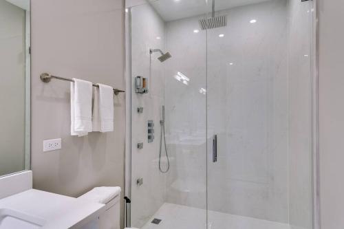a white bathroom with a shower and a sink at 2 Newly Built Luxury Condos with Private Roofdeck in Chicago