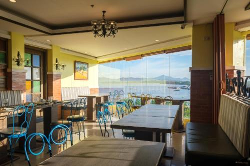 a restaurant with tables and chairs and a large window at Sunlight Hotel Puerto Princesa in Puerto Princesa City
