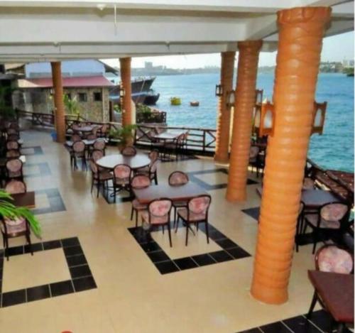 a restaurant with tables and chairs and the water at Mombasa Comfort House, Old Town in Mombasa