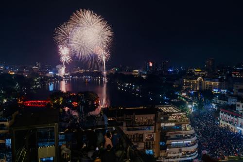a firework display over a river at night at MAY DE VILLE Lakeside Hotel in Hanoi
