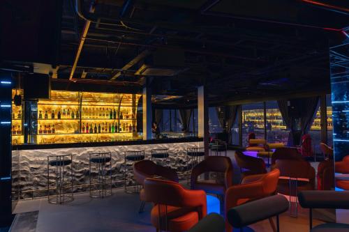 a bar with red chairs and a wall of wine bottles at MAY DE VILLE Lakeside Hotel in Hanoi