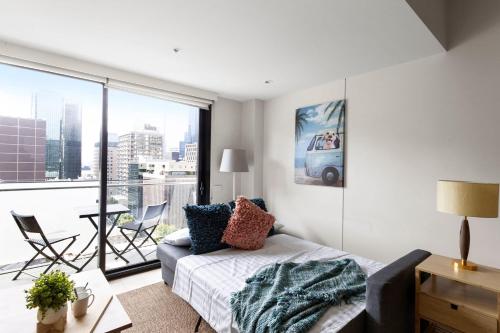 - un salon avec un lit et une grande fenêtre dans l'établissement A Cozy & Comfy 2BR Apt Near Victoria Market, à Melbourne