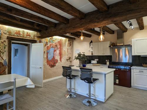 une cuisine avec des armoires blanches et des tabourets de bar dans l'établissement Gîte de charme rénové à Châteauroux, jardin privé, jusqu'à 10 pers, proche centre et Belle-Isle - FR-1-591-581, à Châteauroux