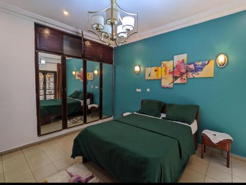 um quarto com uma cama verde e uma parede azul em THE GOLF RESIDENCES YAOUNDE em Iaundé