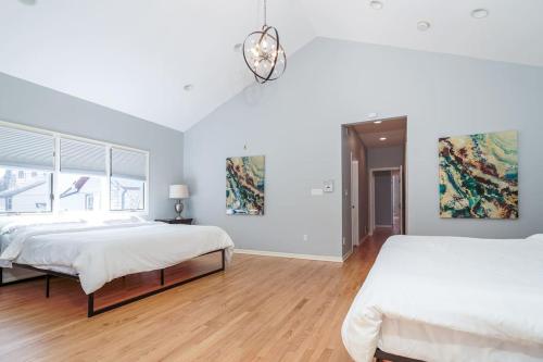 Habitación blanca con 2 camas y lámpara de araña. en Eclectic Stylish and Cozy Milwaukee Home en Milwaukee