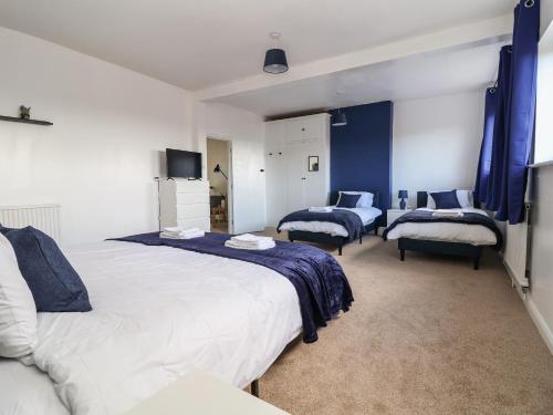 1 dormitorio con 2 camas y cortinas azules en Mariners Lee, en Llandudno