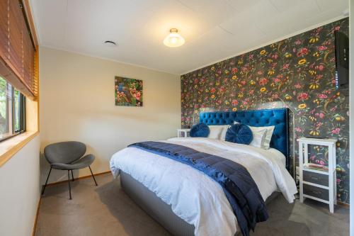 a bedroom with a blue bed with a floral wallpaper at Alpine Rock B&B in Te Anau