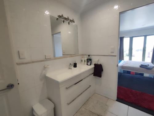 a white bathroom with a sink and a mirror at Panoramic vista on burns in New Plymouth