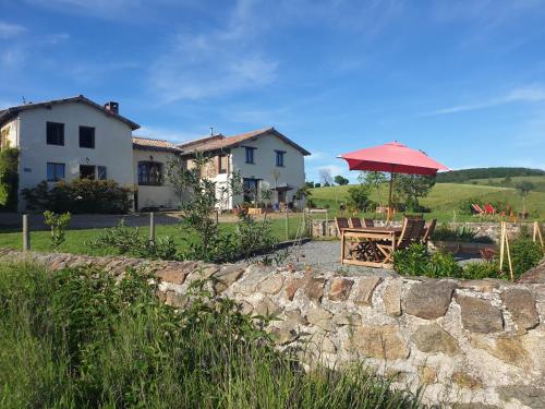 un mur en pierre avec une table et un parasol dans l'établissement Maison l'âne vert, à Lay
