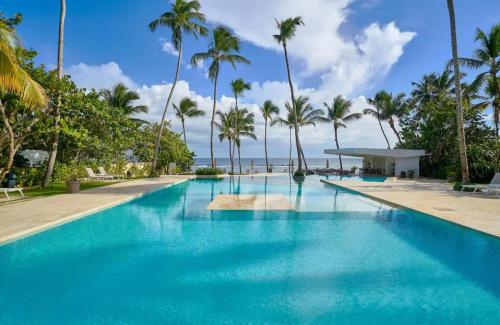 - une piscine avec des palmiers et l'océan dans l'établissement Juan Dolió Service Vip, à Saint-Domingue