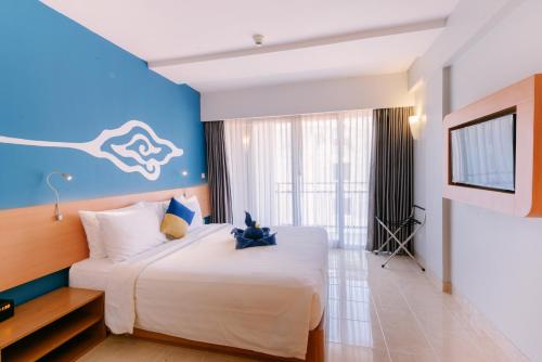 1 dormitorio con 1 cama grande y pared azul en Kuta Beach Hotel, en Kuta