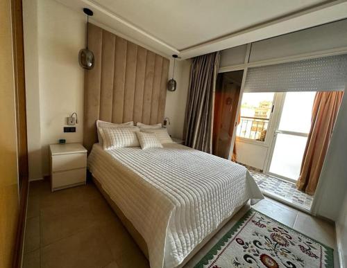 a bedroom with a bed and a large window at Luxueux appartement au centre de Rabat in Rabat