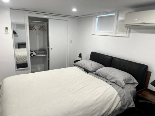 WoodhavenにあるModern & cozy basement apartment near JFK airportのベッドルーム(白いベッド1台、鏡付)
