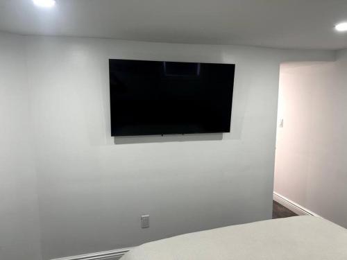 WoodhavenにあるModern & cozy basement apartment near JFK airportの白壁の薄型テレビ