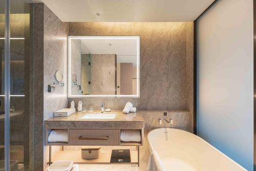 bagno con vasca, lavandino e specchio di ZhouShan Poly Senbo Nature Park & Resort a Zhoushan