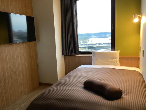 una camera d'albergo con un letto con un cuscino sopra di Mito Hotel Season a Mito
