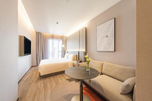 a hotel room with a couch and a bed at Atour S Hotel Shanghai Lujiazui Expo Center in Shanghai