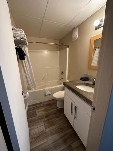 a bathroom with a toilet and a sink and a tub at West Coast Motel on the Harbour in Ucluelet