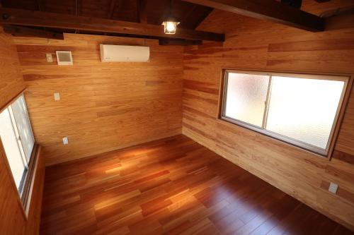 an empty room with a window and wooden walls at Jisso Youth travel village in Yamano