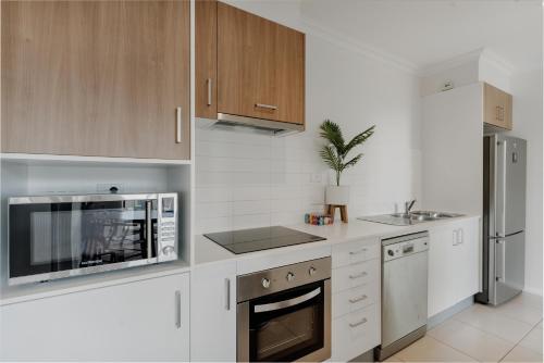 a white kitchen with a microwave and a refrigerator at Peaceful 1-Bed Apartment Close to Lonsdale St in Canberra
