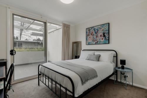 um quarto branco com uma cama e uma janela em Peaceful 1-Bed Apartment Close to Lonsdale St em Camberra
