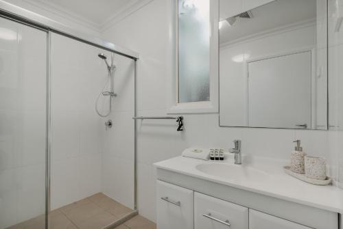 uma casa de banho branca com um lavatório e um chuveiro em Peaceful 1-Bed Apartment Close to Lonsdale St em Camberra