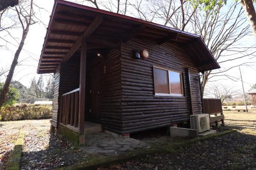 a small log cabin with a window and a bench at Jisso Youth travel village in Yamano