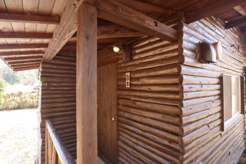 a wooden cabin with a door and a window at Jisso Youth travel village in Yamano