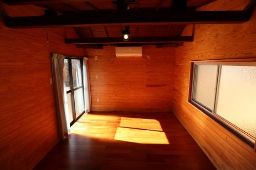 an empty room with a window and a wooden wall at Jisso Youth travel village in Yamano