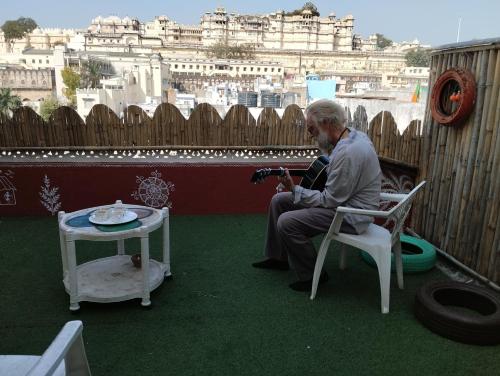 a man sitting in a chair taking a picture of a city at City and Palace view guest House in Udaipur