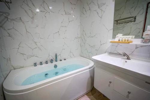 a white bathroom with a tub and a sink at Baan Plaifah Khao Yai Hotel in Khao Yai