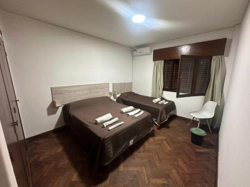 Habitación con 2 camas y una silla. en Hostel San Vicente en Salta