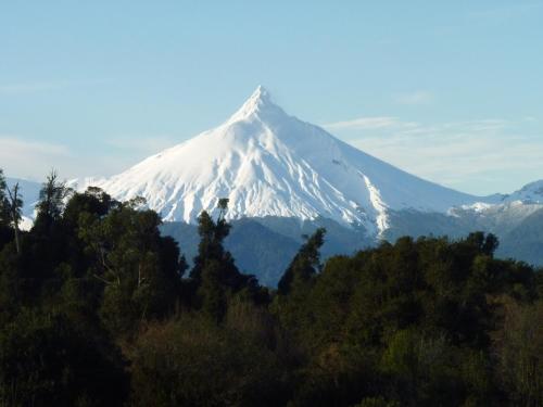 a snow covered mountain with trees in the foreground at Lodge El Taique in Puyehue