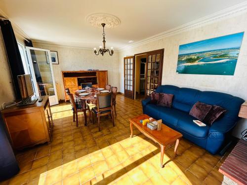 ein Wohnzimmer mit einem blauen Sofa und einem Tisch in der Unterkunft "NAUSICAA" Maison 6 personnes, 2 chambres, jardin clos, proche plage et forêt, chiens acceptés in Talmont