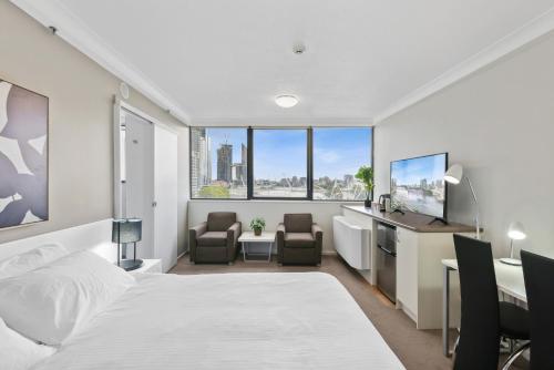 Schlafzimmer mit einem Bett, einem Schreibtisch und Stühlen in der Unterkunft Central Brisbane Studio with Stunning River Views in Brisbane