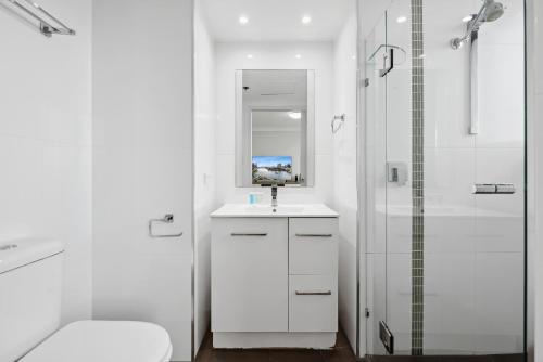 uma casa de banho branca com um lavatório e um chuveiro em Central Brisbane Studio with Stunning River Views em Brisbane