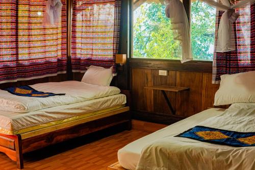 two beds in a room with two windows at A Dế Homestay Sơn Tra in Phong Thổ