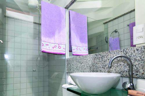 a bathroom with a sink and purple towels at Flat no Nannai Residence Muro Alto in Porto De Galinhas