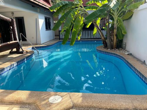 a blue swimming pool with a palm tree in it at Nirvana pool villa 2 in Nong Prue