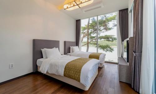 1 Schlafzimmer mit 2 Betten und einem großen Fenster in der Unterkunft Goseong hansan marina in Goseong