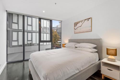- une chambre blanche avec un grand lit et une fenêtre dans l'établissement 2-Bed Inner-City Pad Bright with Panoramic Views, à Melbourne