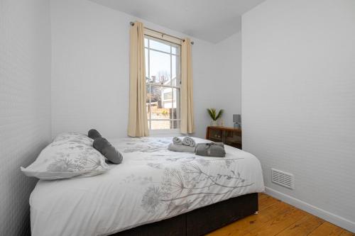 a white bedroom with a bed with a window at Refurbished Double Bedroom in London