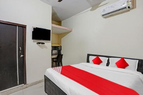a bedroom with a bed with red pillows and a tv at The Krishna Stays in Mathura