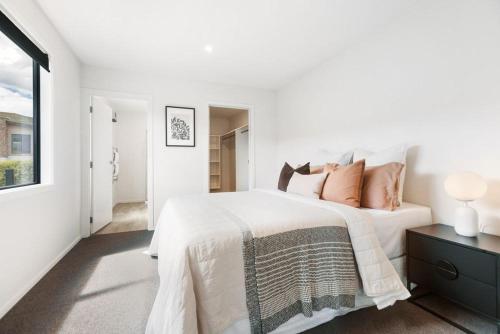 a white bedroom with a large bed and a window at Magic Central Wanaka Living in Wanaka