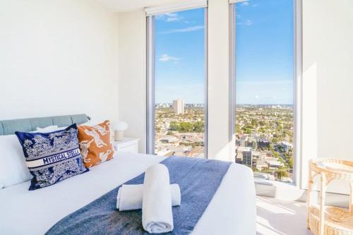 a bedroom with a white bed with a large window at Modern 2B APT BayViews*Pool*GYM in Melbourne