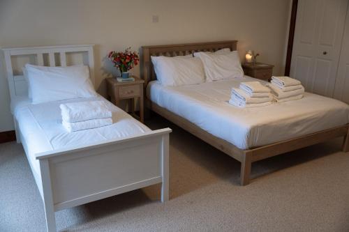 two beds in a room with towels on them at Woodlands House in Ballachulish