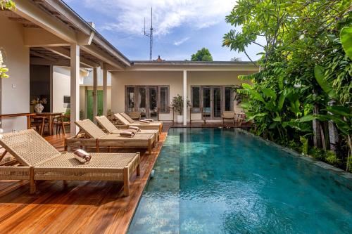 a swimming pool with lounge chairs and a house at RIYURI GUESTHOUSE in Tumbak Bayuh
