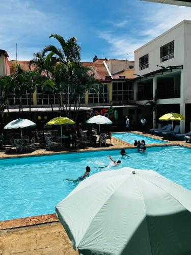 a group of people swimming in a swimming pool with an umbrella at Hôtel - Appartement meublé " LES FLOTS BLEU " in Antananarivo