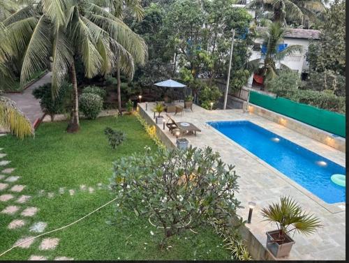 a backyard with a swimming pool and a yard with a yard at The Chapters Villa in Alibag